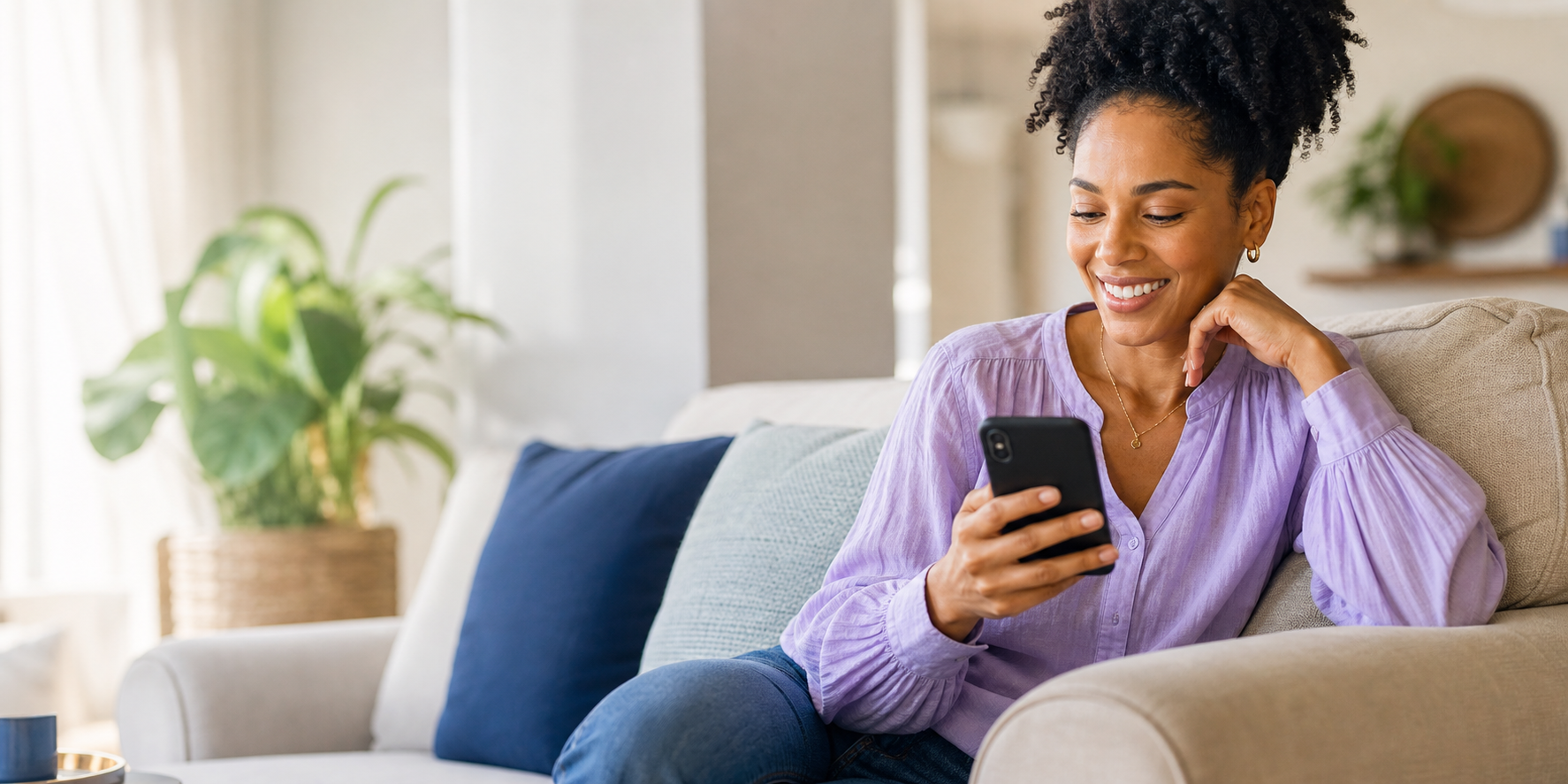 A woman smiling with relief while looking at her phone at home